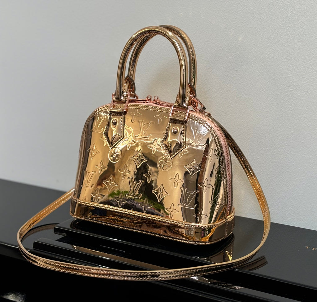 Louis Vuitton bag with structured top handles, gold metallic monogram pattern, front clasp.