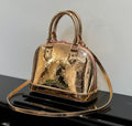 Louis Vuitton bag with structured top handles, gold metallic monogram pattern, front clasp.