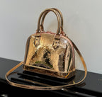 Louis Vuitton bag with structured top handles, gold metallic monogram pattern, front clasp.
