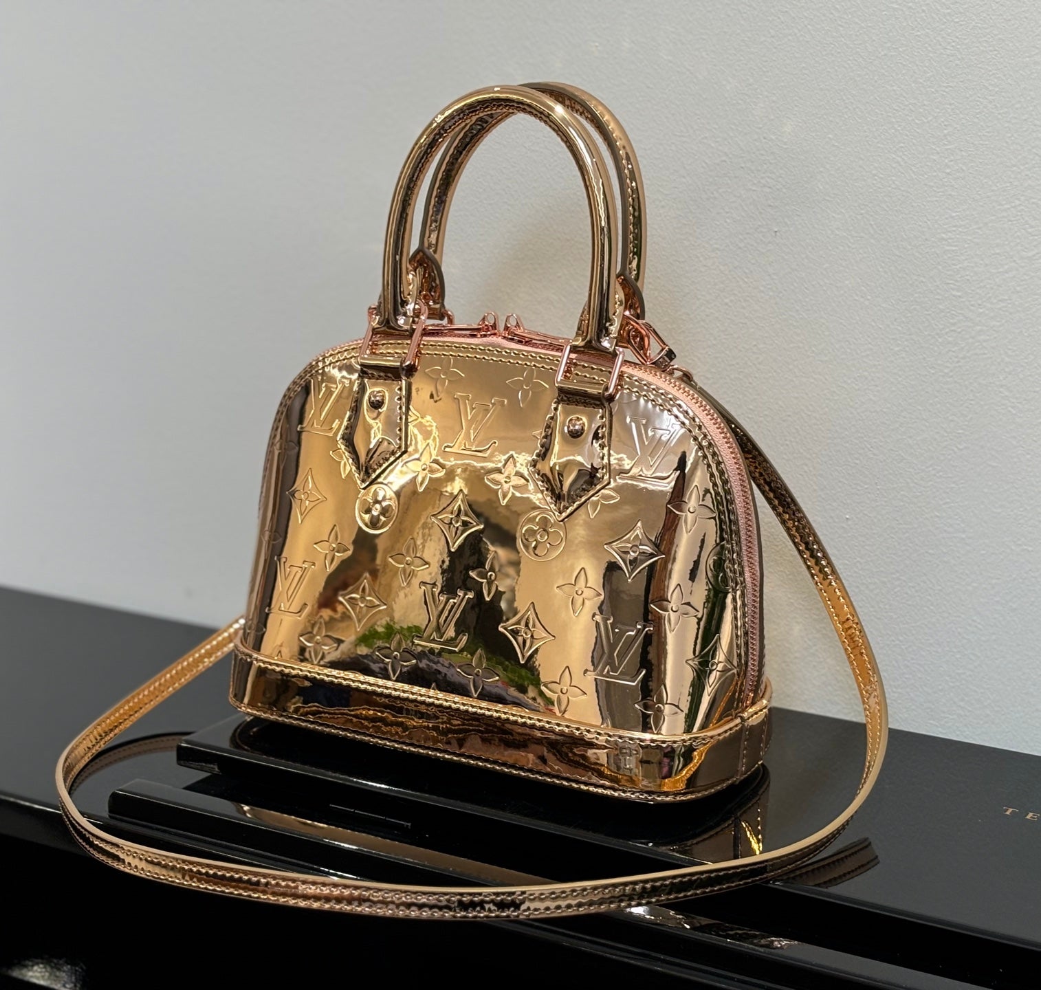 Louis Vuitton bag with structured top handles, gold metallic monogram pattern, front clasp.