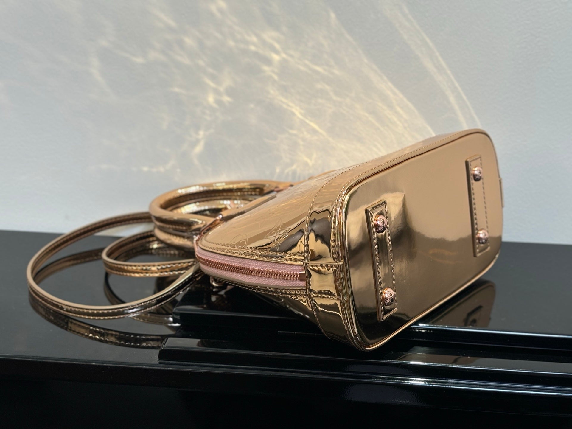 Louis Vuitton bag with front gold-tone clasp and top handle, pale pink body, zipper top.