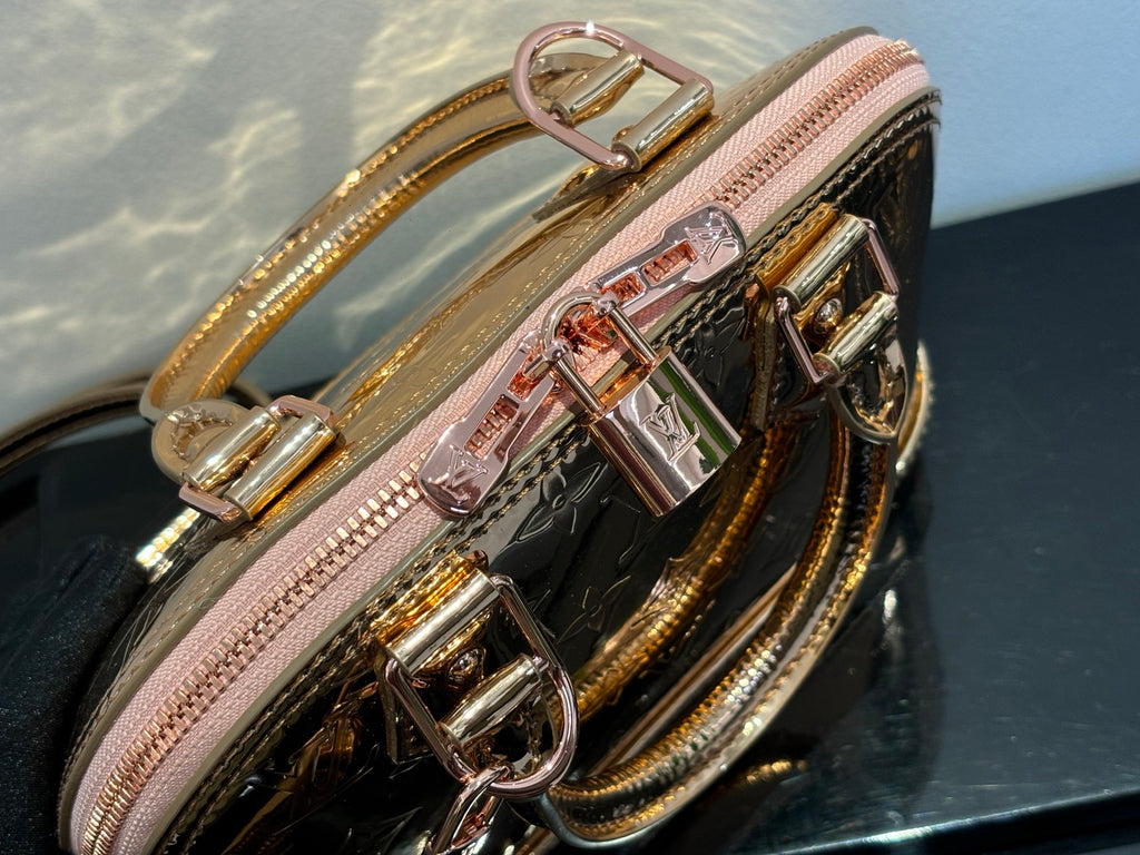Louis Vuitton bag close-up of top hardware and chain strap, pink zipper, gold accents.