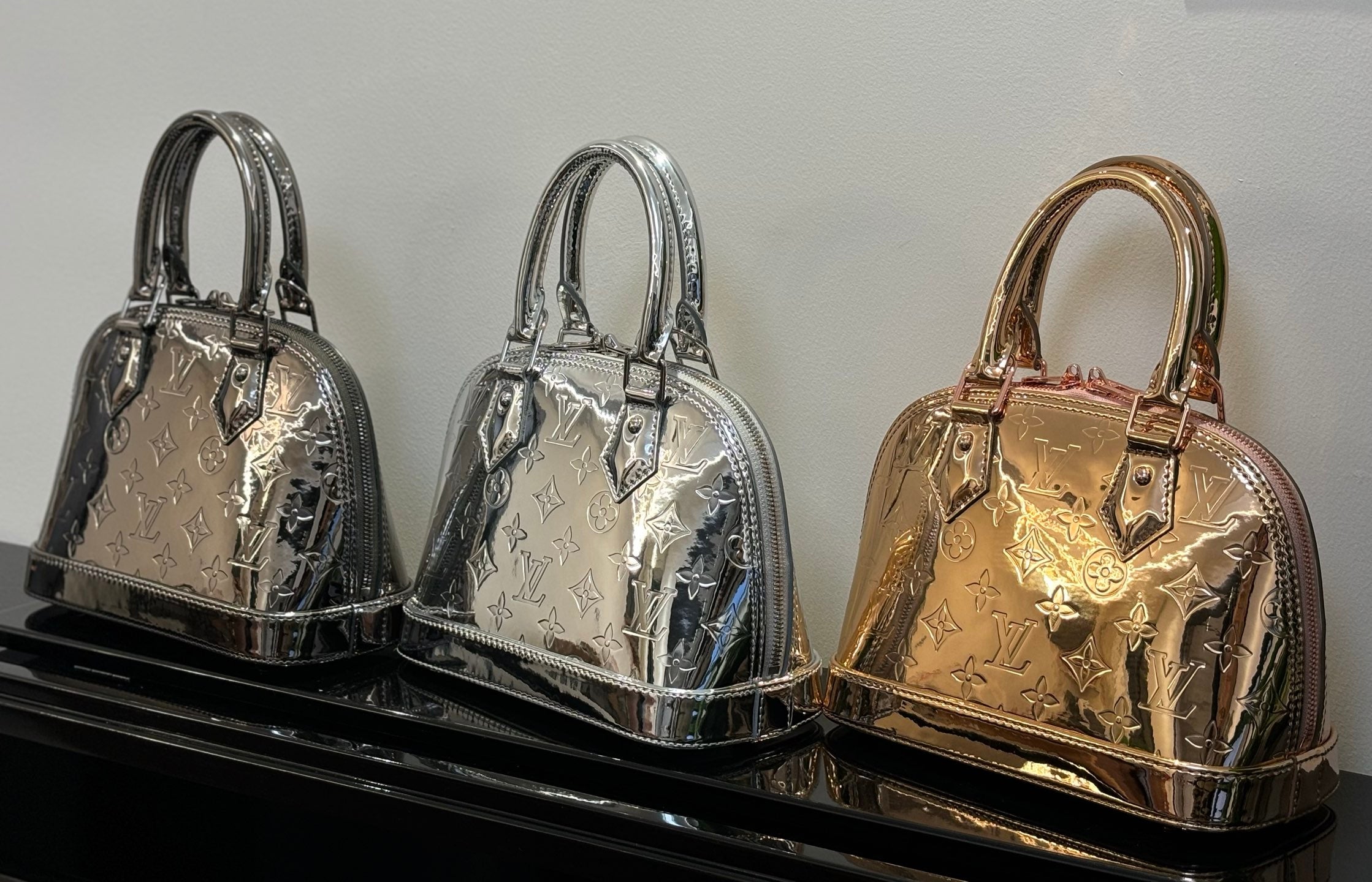 Louis Vuitton bags trio on display: silver and gold metallic monogram with top handles.