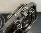 Louis Vuitton handbag close-up of zipper pulls and glossy hardware on metallic silver