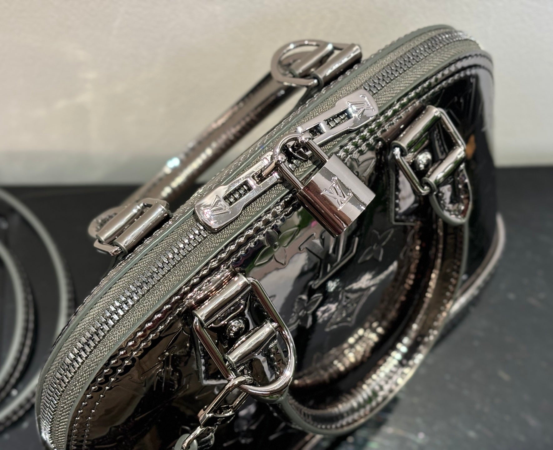 Louis Vuitton handbag close-up of zipper pulls and glossy hardware on metallic silver