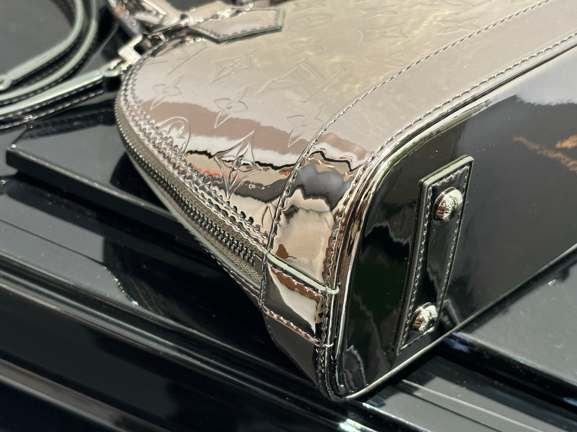 Louis Vuitton handbag close-up of front flap and shiny hardware, metallic silver