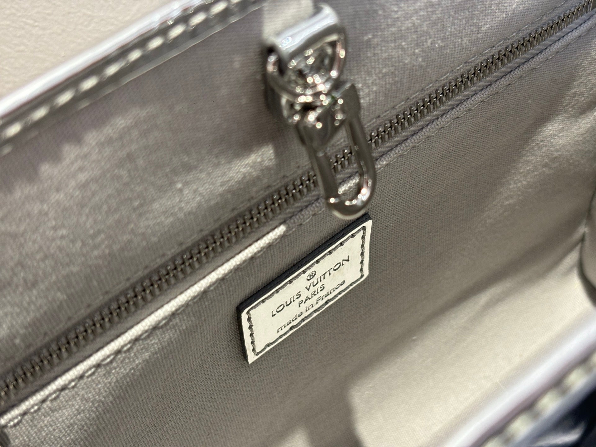 Louis Vuitton monogram handbag interior pocket label with zipper pull, metallic silver