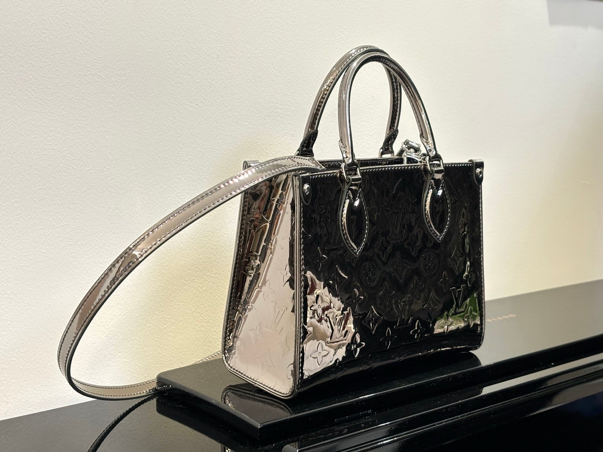 Louis Vuitton handbag with shoulder strap, glossy dark exterior with multicolor printed motifs
