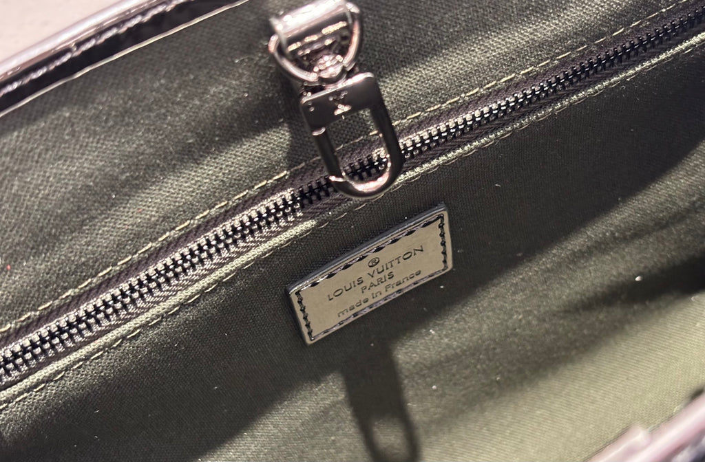 Louis Vuitton handbag zipper pull and brand patch label on dark leather