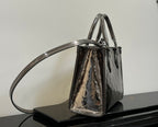 Louis Vuitton handbag with top handles and shoulder strap, glossy dark and metallic graphic pattern