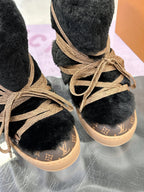 Close-up of black faux-fur Louis Vuitton ankle boots with tan lace-up front