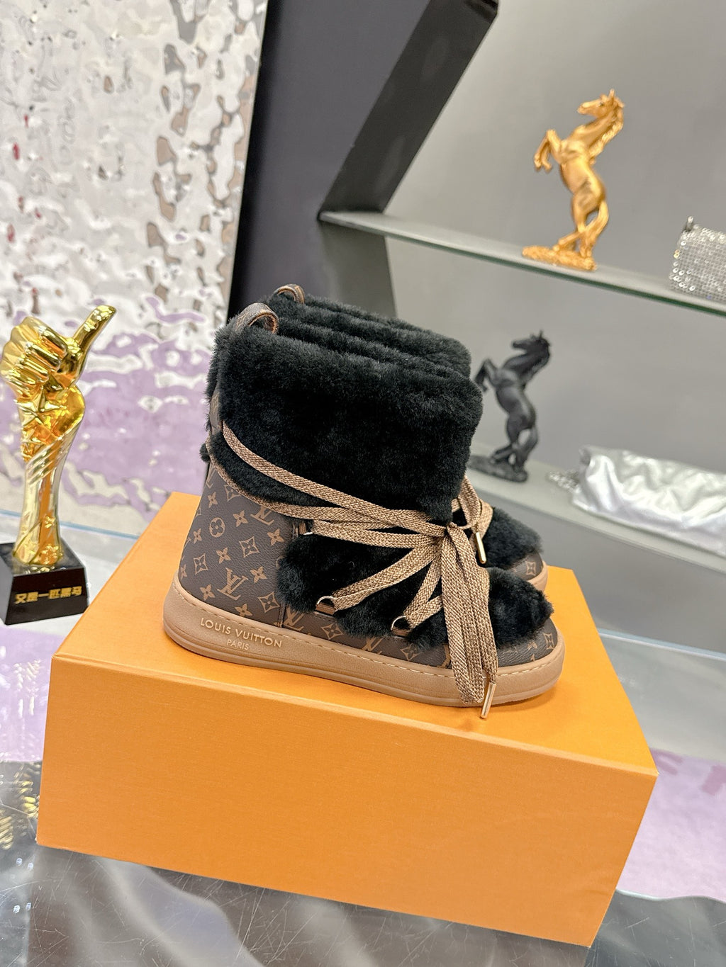 Black faux-fur lace-up ankle boots with tan laces and monogram trim