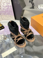 Two black faux-fur lace-up ankle boots with tan laces on a box
