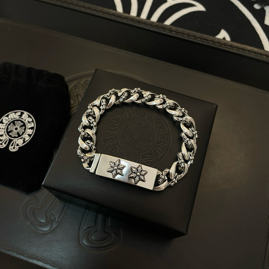 Silver-toned chain bracelet on display, rectangular clasp with two cross-flower emblems