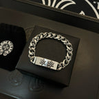 Silver-toned chain bracelet on display, rectangular clasp with two cross-flower emblems