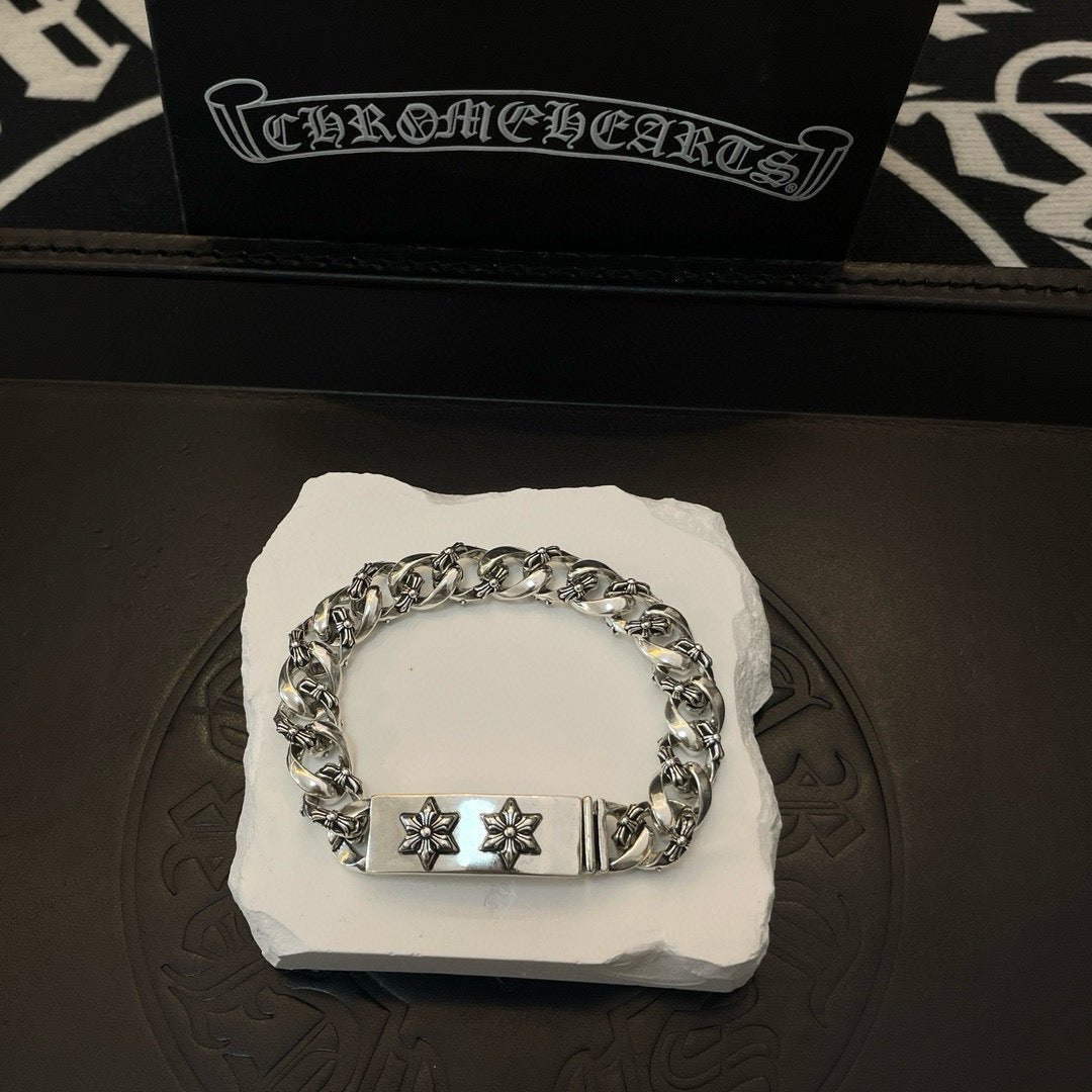 Silver-toned chain bracelet with rectangular center clasp and two cross-flower emblems