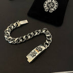 Silver-toned chain bracelet with rectangular center clasp plate and two cross-flower emblems