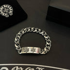 Silver-toned chain bracelet with rectangular center tag and two cross-flower emblems