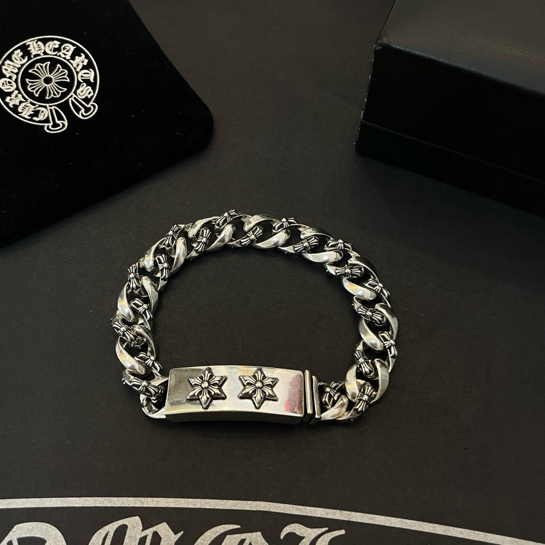 Silver-toned chain bracelet with rectangular center tag and two cross-flower emblems