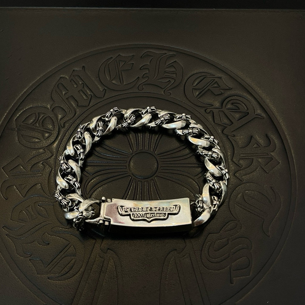 Silver-toned chain bracelet with rectangular tag clasp and two cross-flower emblems
