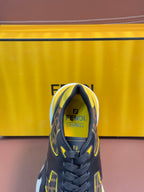 Fendi unisex sneaker close-up at toe, dark FF upper with yellow accents and lace-up front.