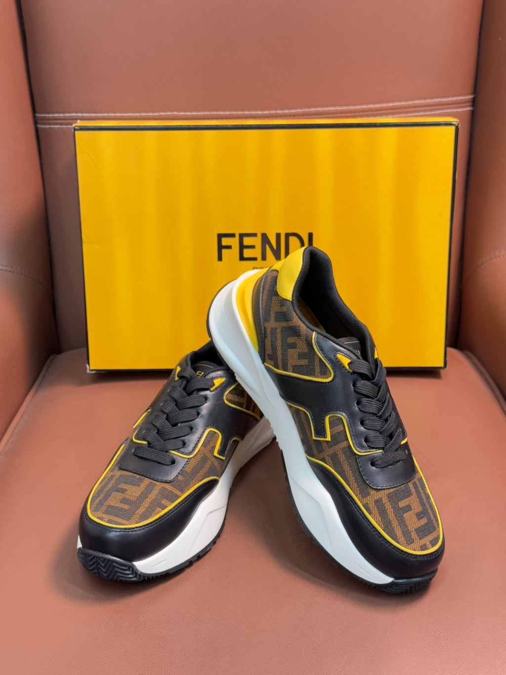 Fendi unisex sneakers close-up, dark upper with FF print, yellow edging, and white midsole.