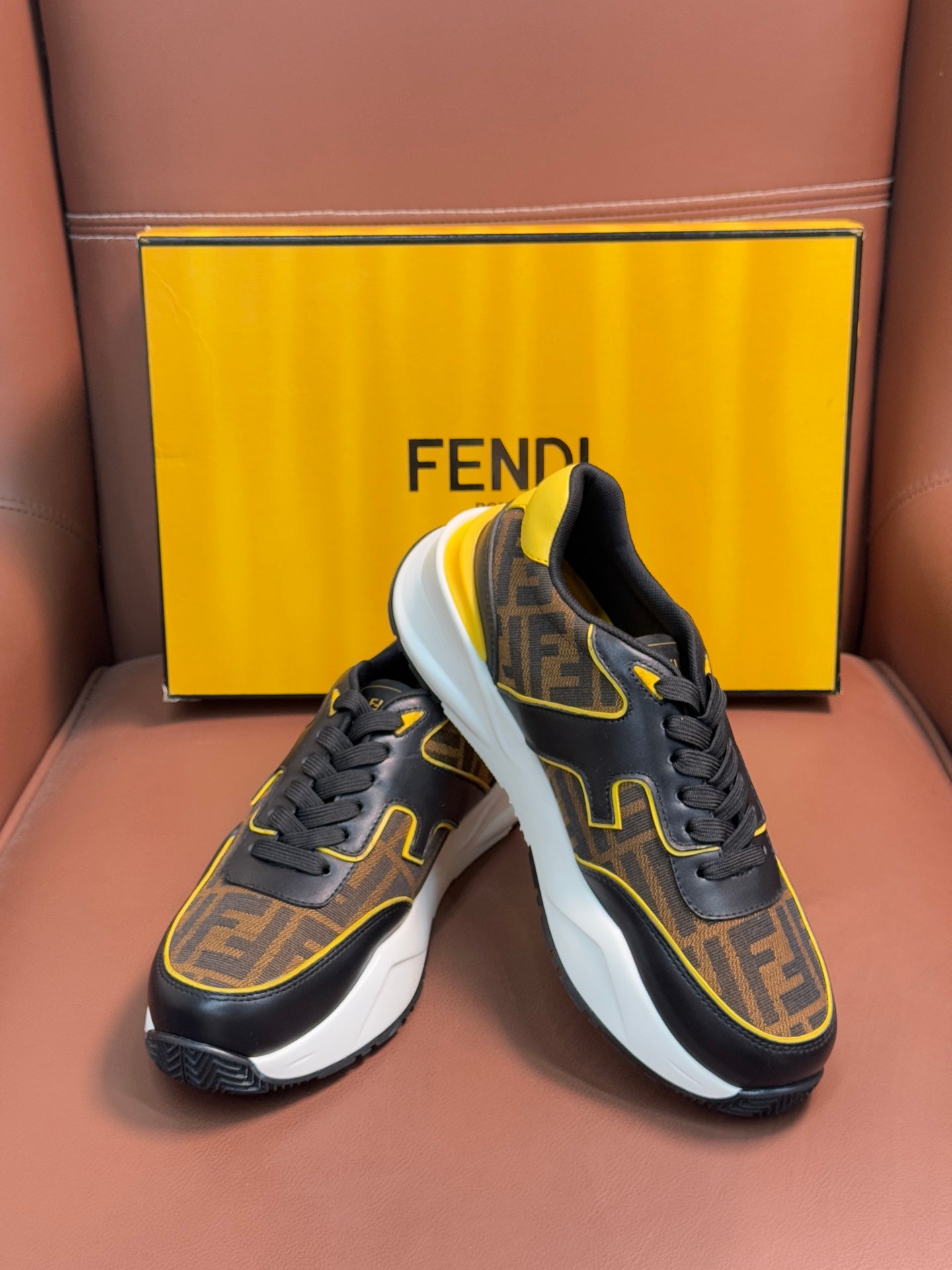 Fendi unisex sneakers close-up, dark upper with FF print, yellow edging, and white midsole.