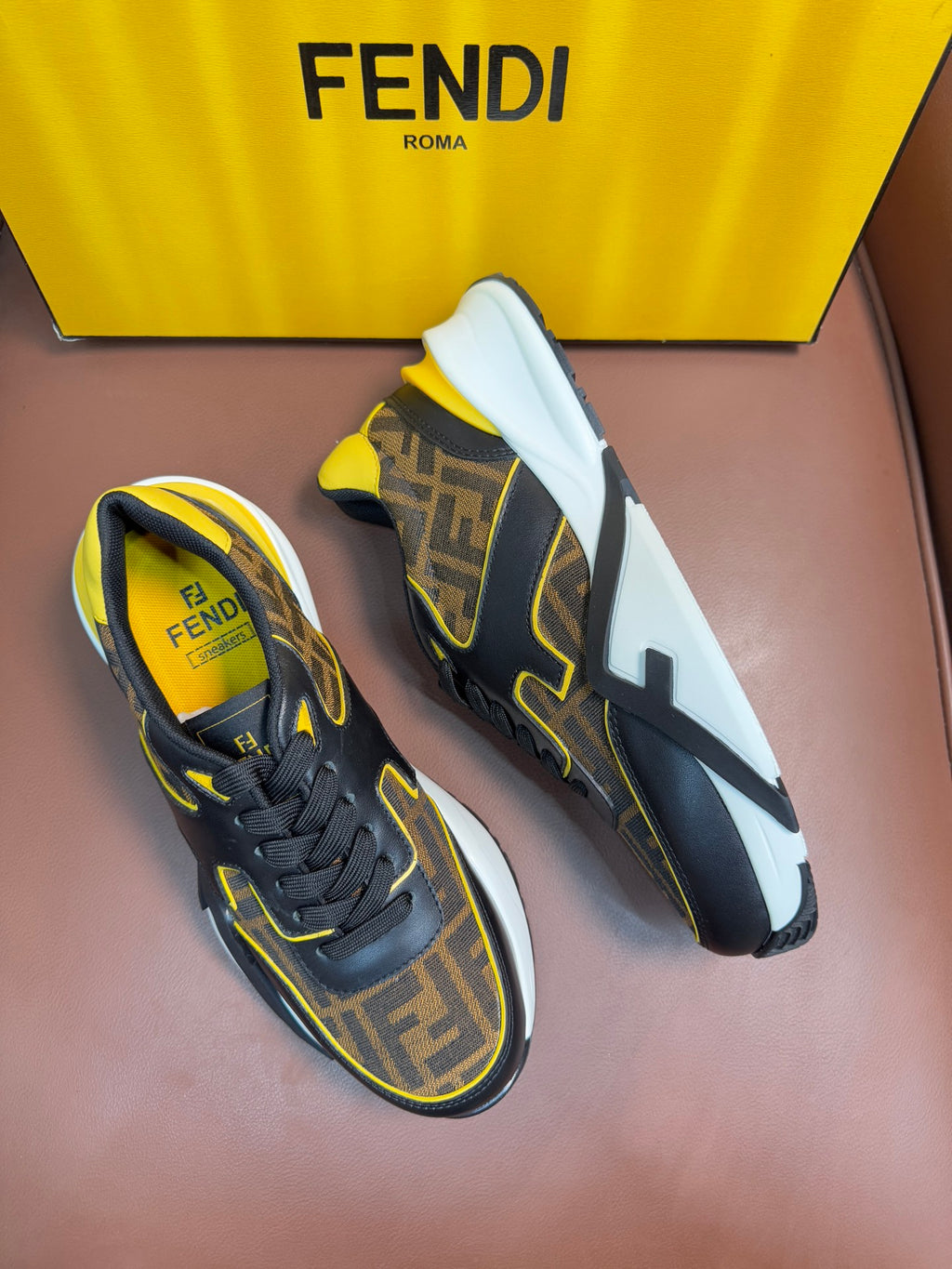 Fendi unisex sneakers, dark upper with FF pattern, yellow accents, and white rubber sole.