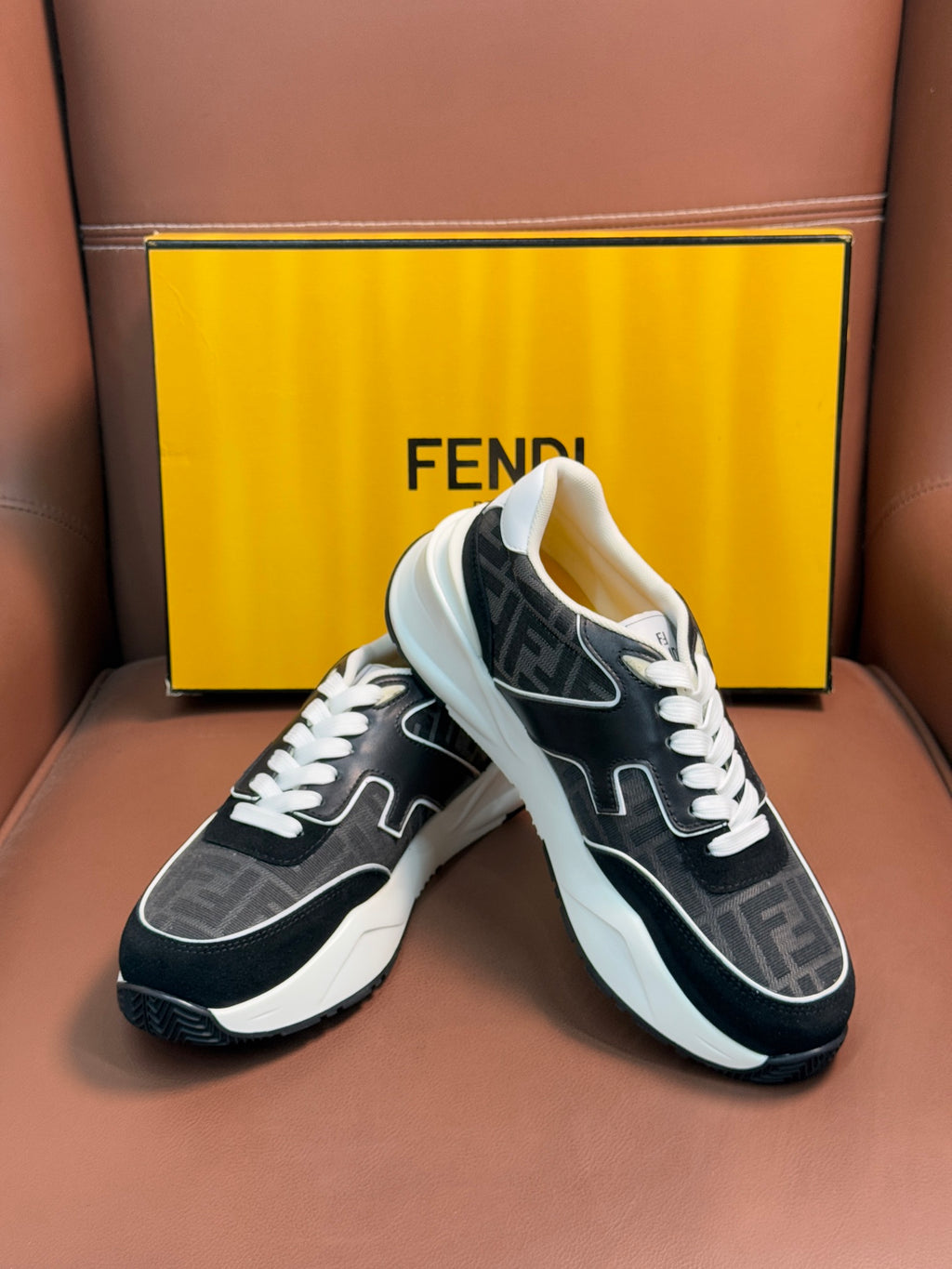 Black and gray Fendi unisex sneakers with white laces and thick white midsole, angled.