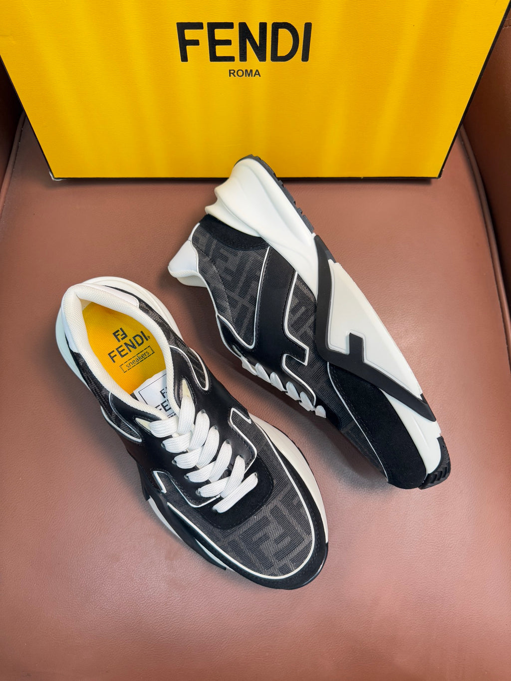 Black and gray Fendi unisex sneakers, angled view, white laces and chunky sole.