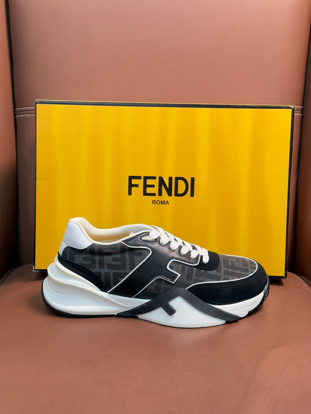 Black and gray Fendi unisex sneakers with white laces and side logo detail, front view.