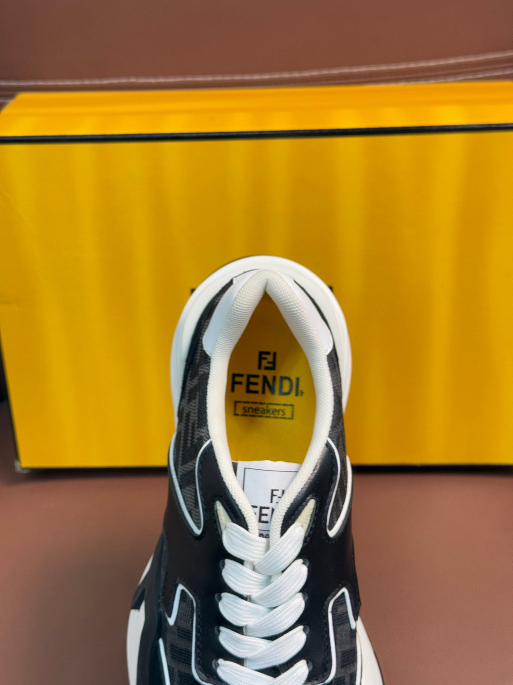 Fendi unisex sneaker tongue and collar detail in black with white laces.