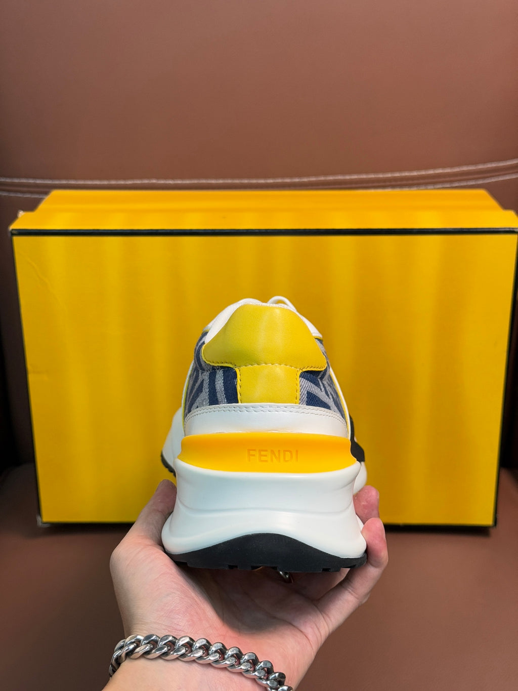 Sneaker heel with yellow collar, white upper, blue FF panel, chunky dark sole.