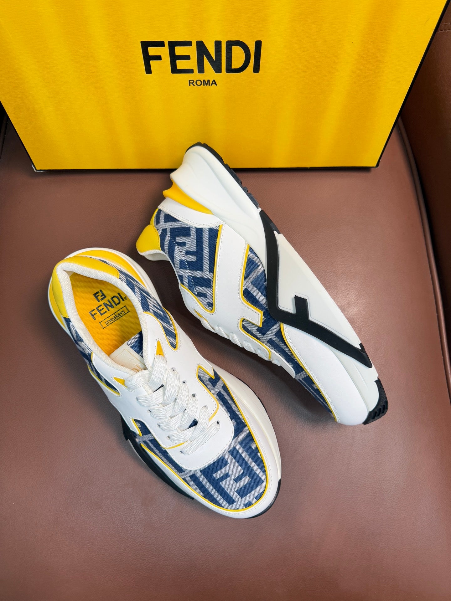 White FENDI sneakers with blue FF panels, yellow trim, lace-up, thick rubber sole.