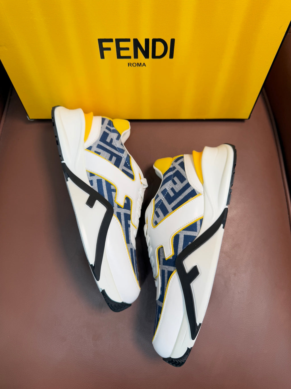 White FENDI sneakers with blue FF side panels, yellow lining, lace-up with chunky sole.