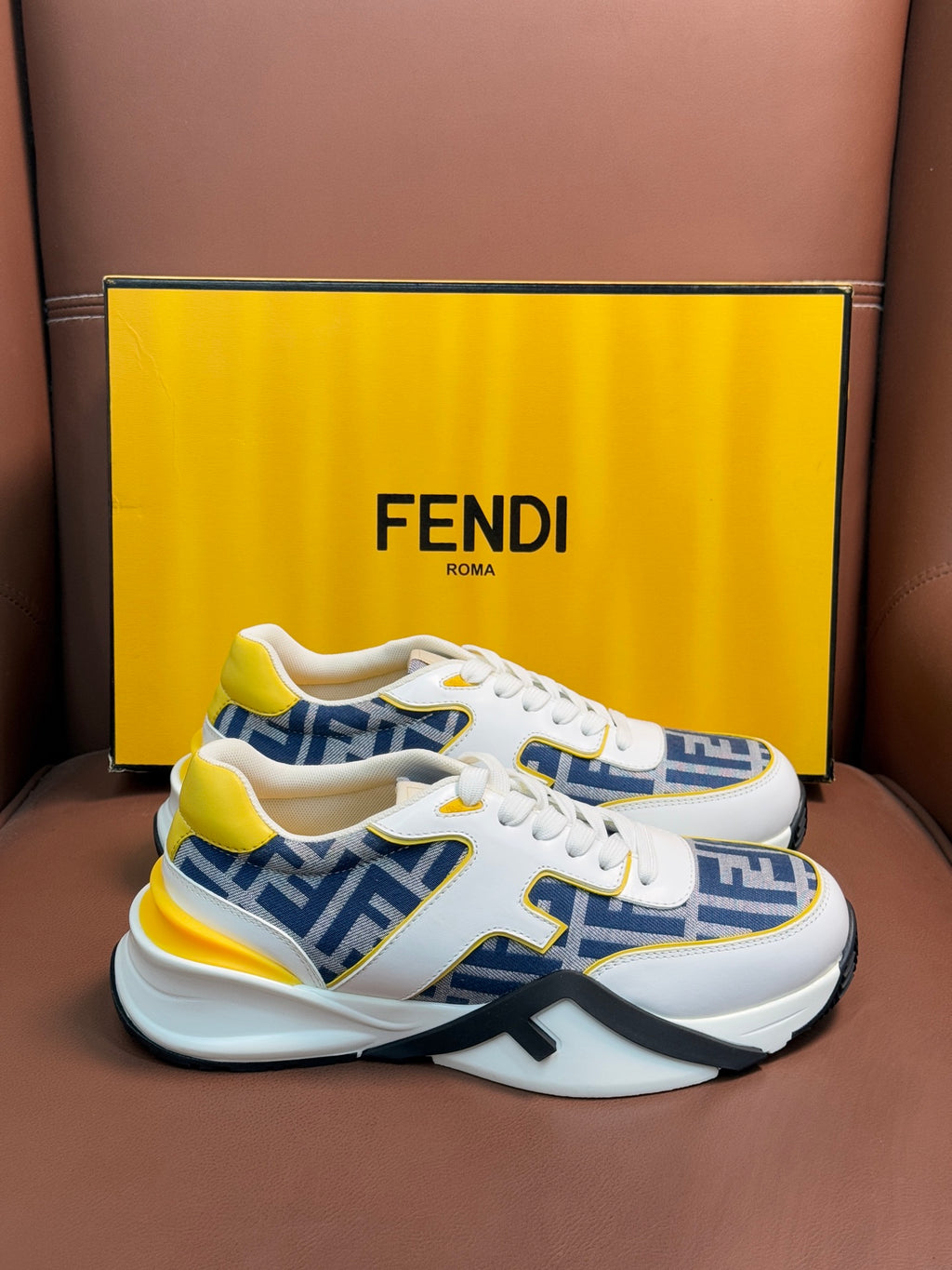 White FENDI low-top sneakers with blue FF panels, yellow accents, lace-up, thick sole.