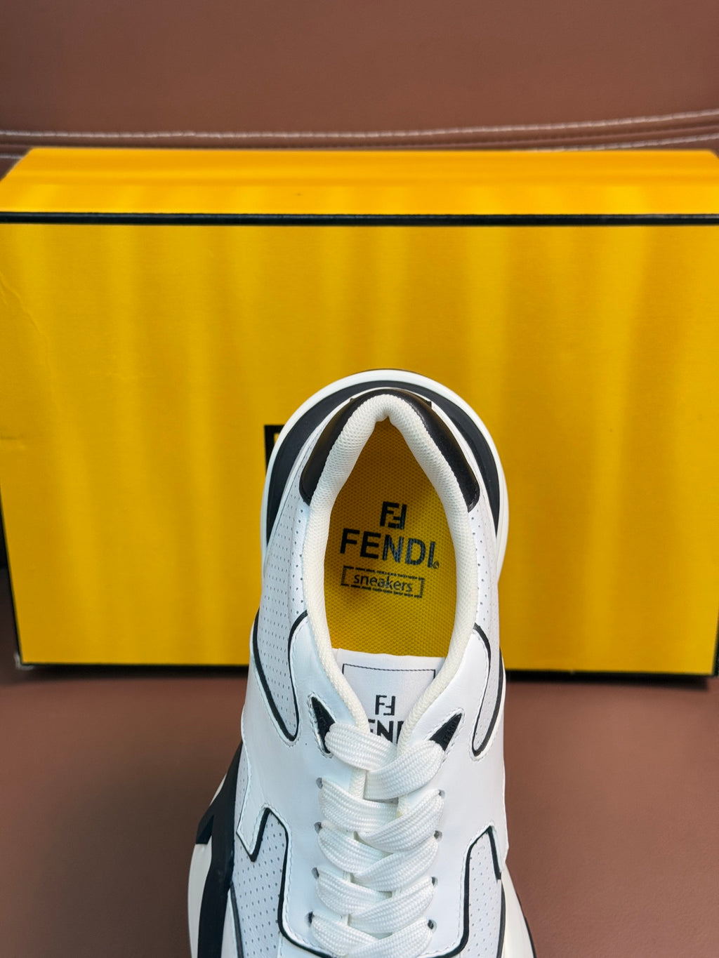 White sneakers with lace-up tongues showing Fendi logo print