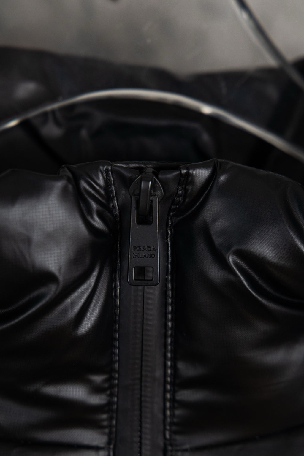 Prada long puffer jacket close-up of front zipper and hood seam detail