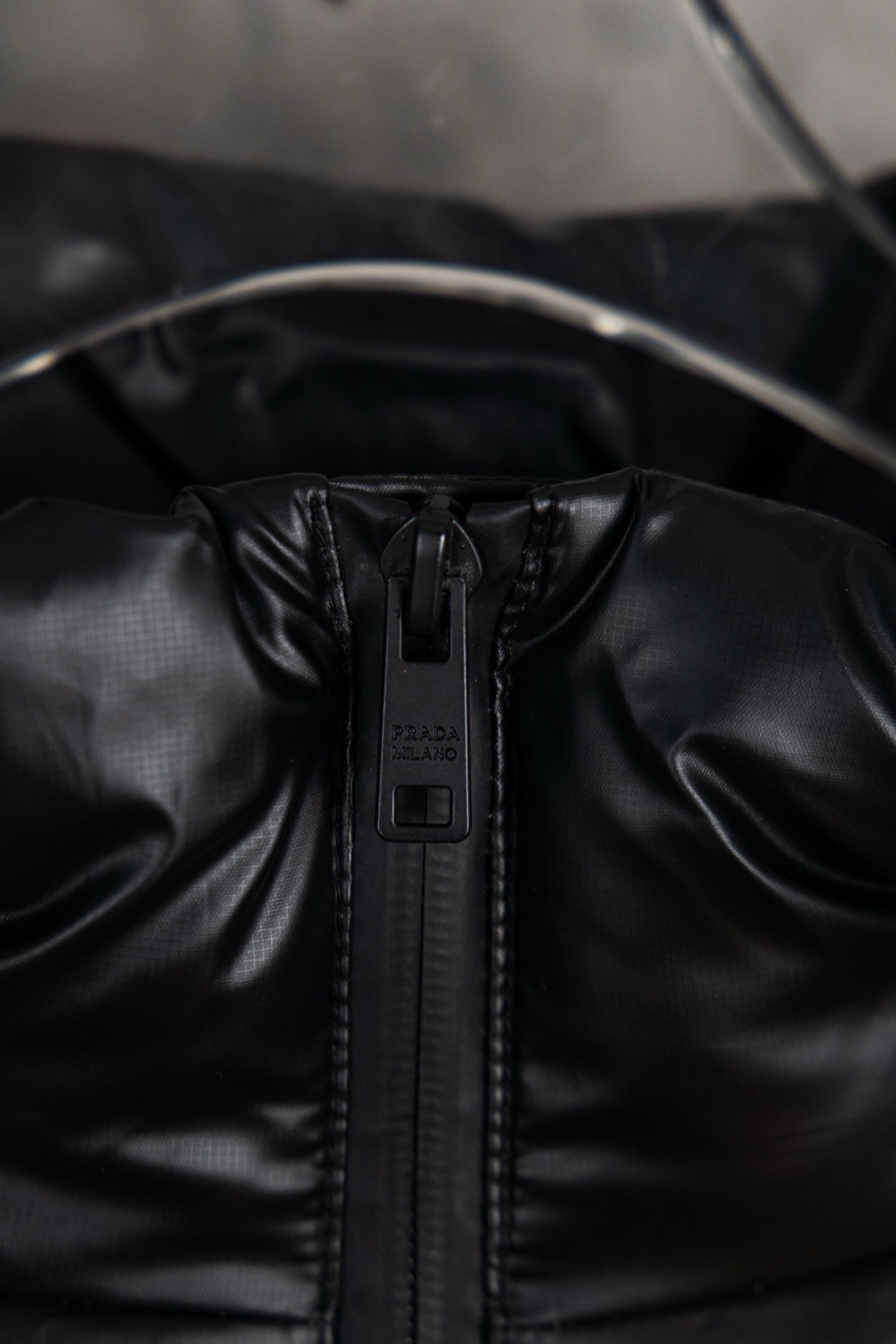 Prada long puffer jacket close-up of front zipper and hood seam detail