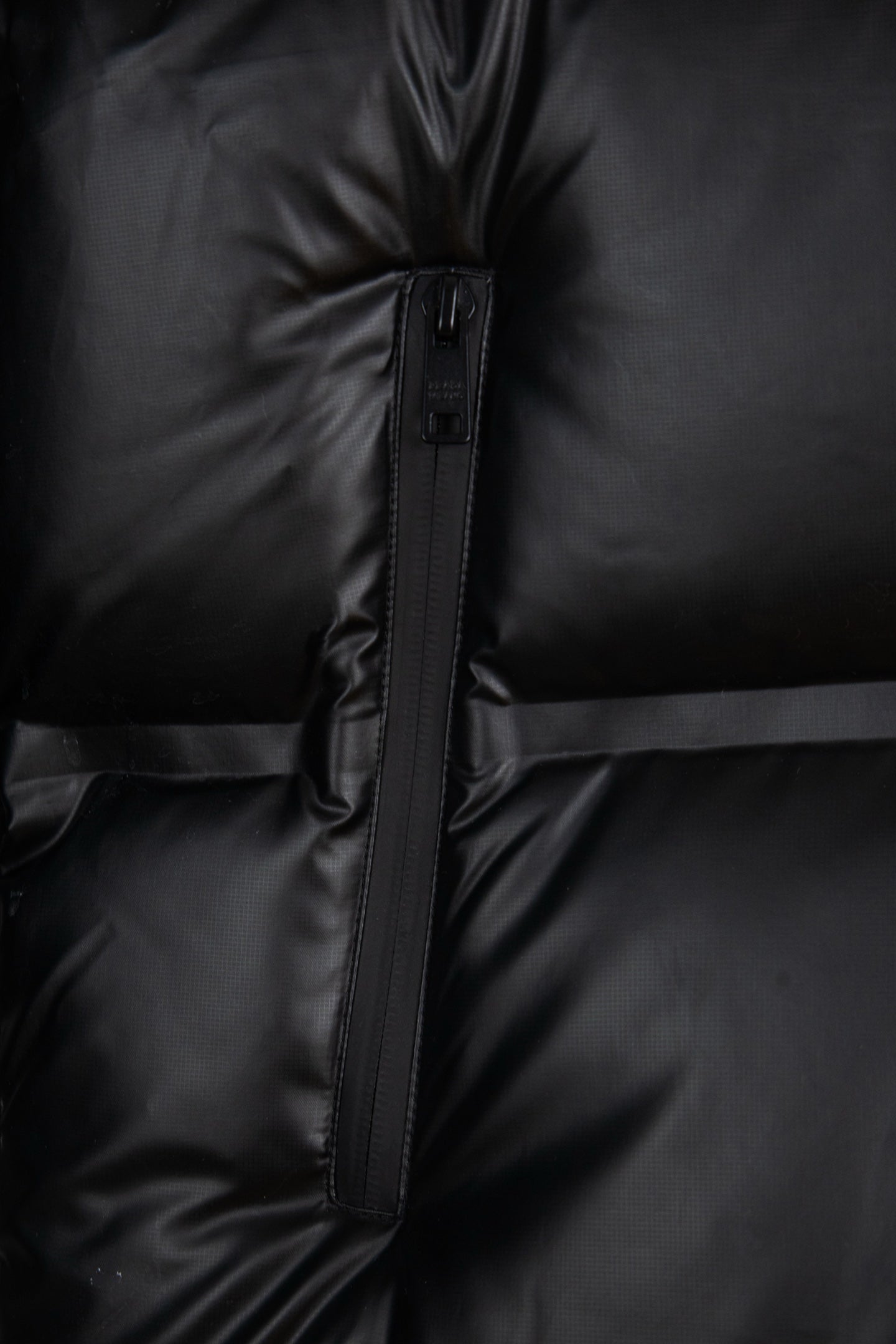 Prada long puffer jacket close-up of front zipper and quilted paneling