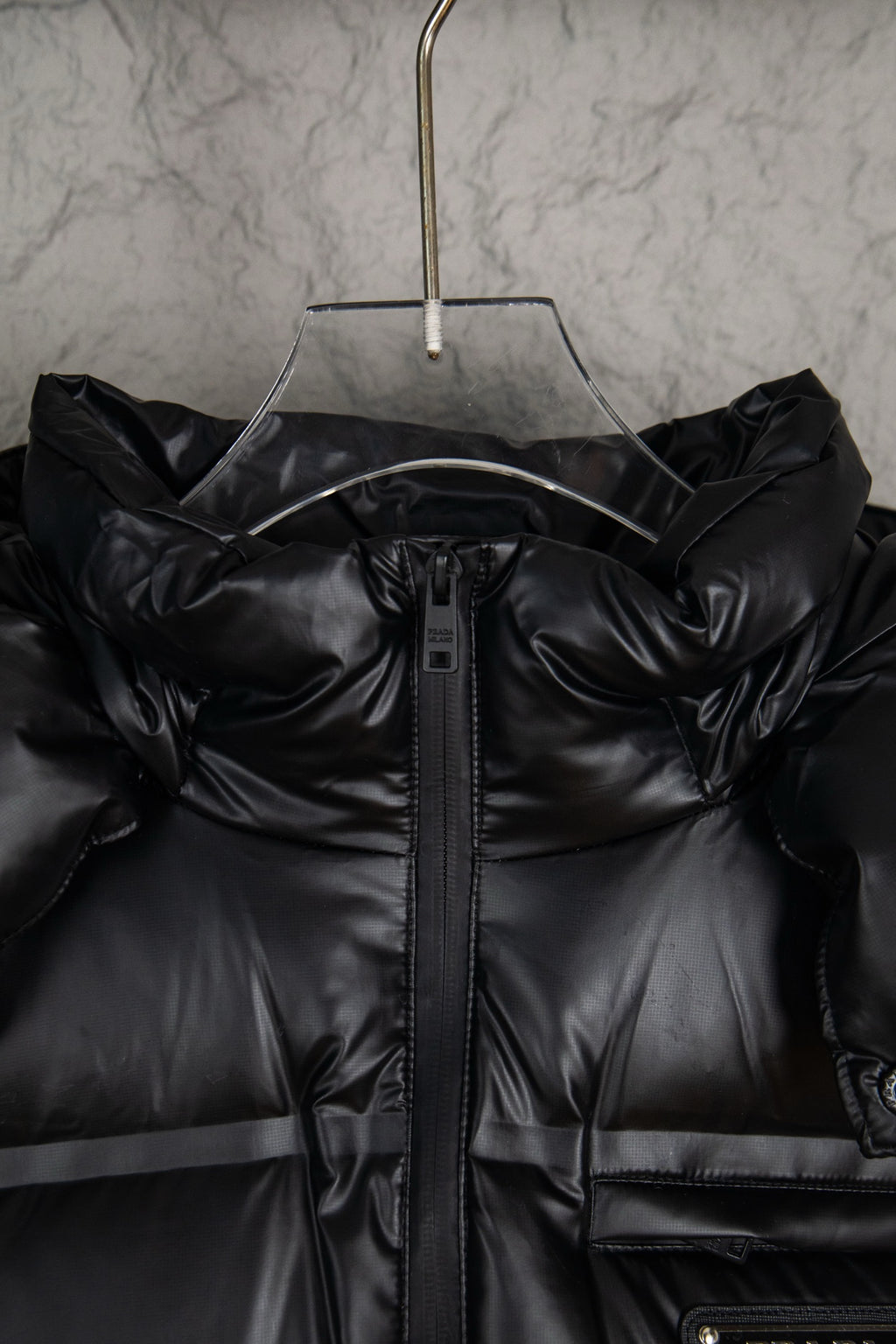Prada long puffer jacket front with hood, black zipper placket, and stitched panels