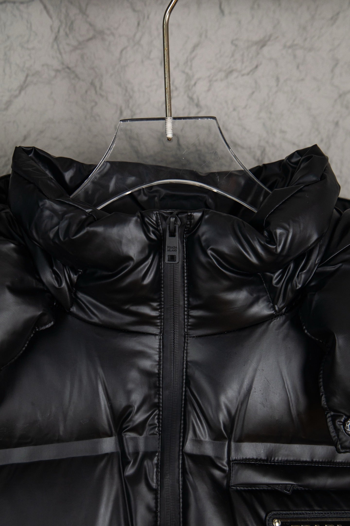 Prada long puffer jacket front with hood, black zipper placket, and stitched panels