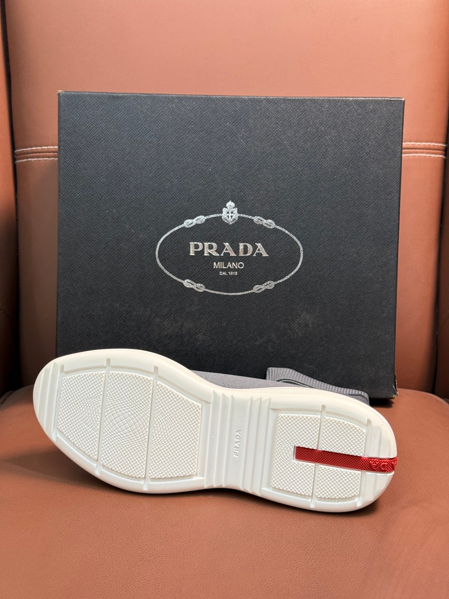 Prada unisex sneaker outsole in white with red heel accent and treaded grip