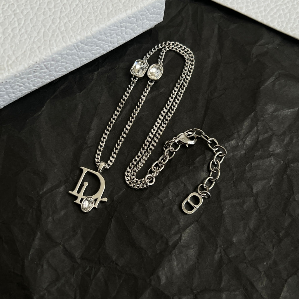 Two silver-tone Dior charm necklaces: D and O logo pendants with gems