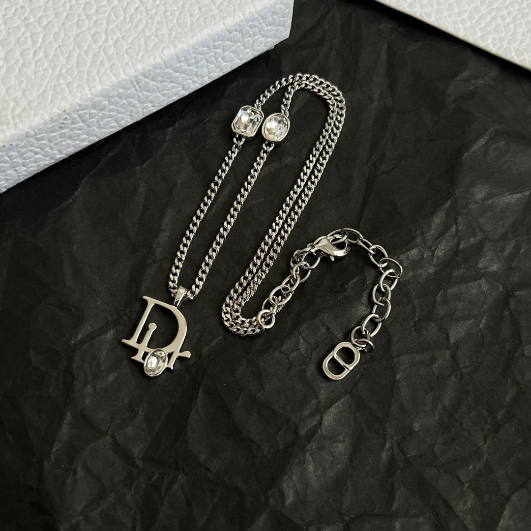 Two silver-tone Dior charm necklaces: D and O logo pendants with gems