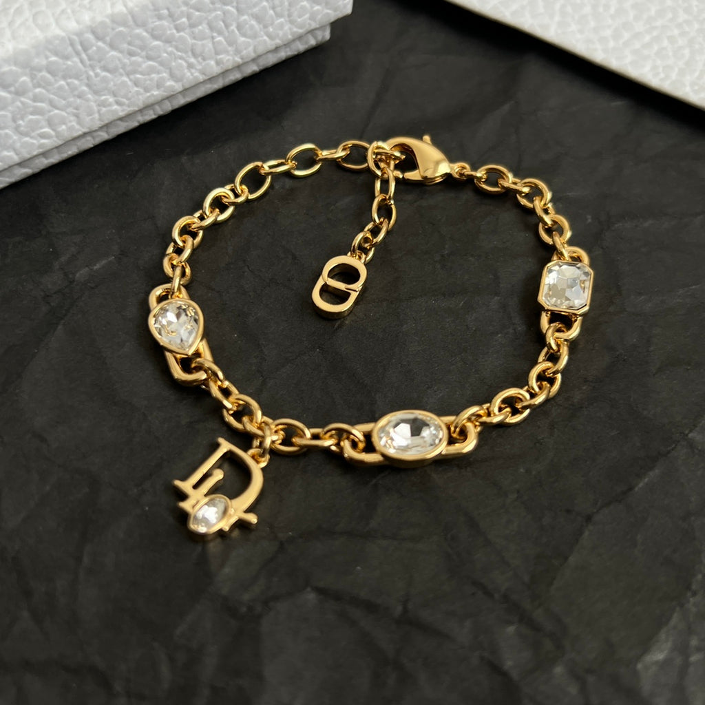 Gold charm bracelet with oval stones, D pendant, and padlock clasp