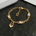 Gold charm bracelet with oval stones, D pendant, and padlock clasp