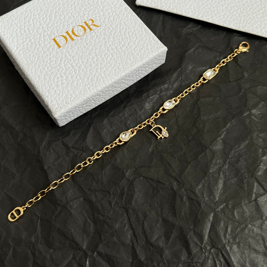Gold charm bracelet with oval stones and D pendant, shown in partial view