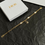 Gold charm bracelet with oval stones and D pendant, shown in partial view