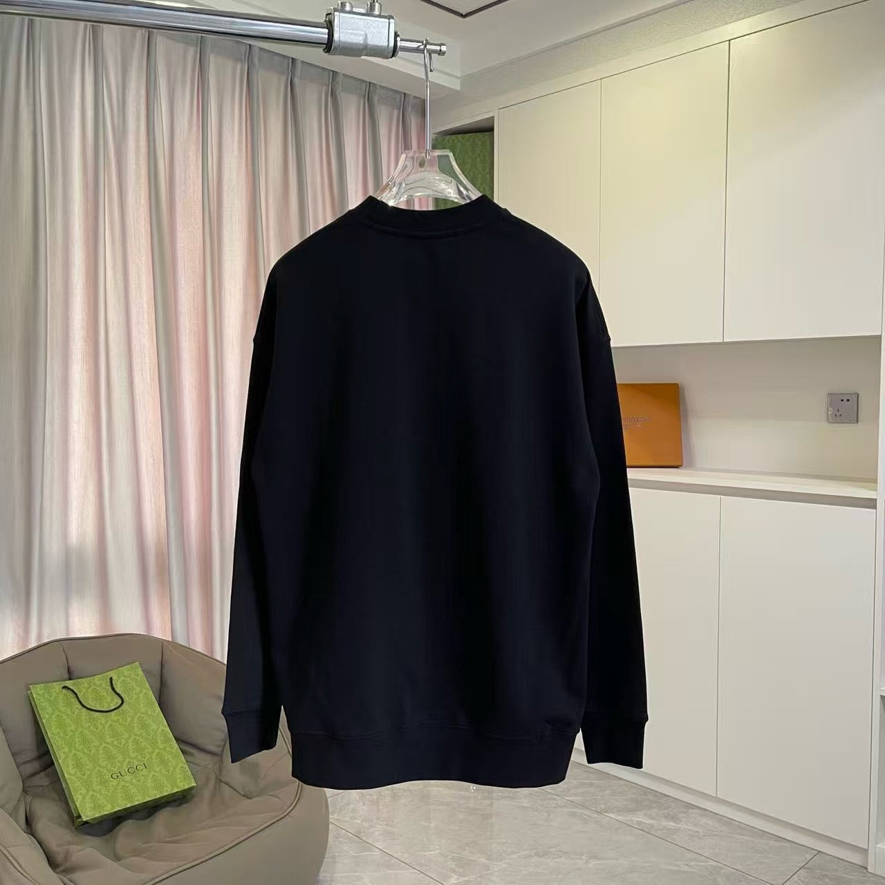 Long-sleeve crewneck sweatshirt, black, plain back view on hanger.